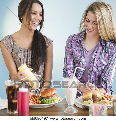 Stock Photo - Teenage girls eating hamburgers and french fries. Fotosearch