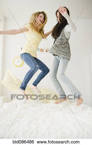 Teenage girls jumping on bed together View Large Photo Image Stock Photograph - Teenage girls jumping on bed together. Fotosearch