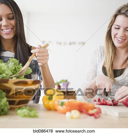 Stock Photo - Teenage girls preparing salad together. Fotosearch