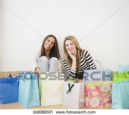 Teenage girls sitting with shopping bags View Large Photo Image Stock Image - Teenage girls sitting with shopping bags. Fotosearch