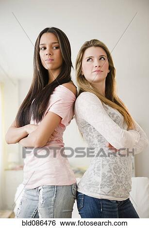 Stock Photograph - Teenage girls standing back to back. Fotosearch