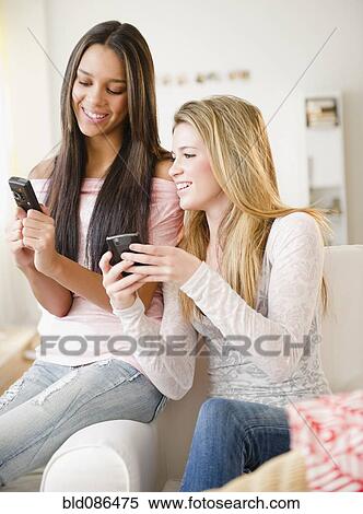 Stock Photography - Teenage girls text messaging on cell phones. Fotosearch
