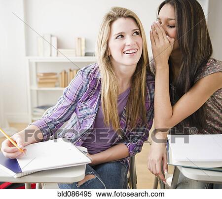 Stock Photography - Teenage girls whispering in classroom. Fotosearch