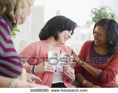 Woman showing friends photographs of her grandchildren View Large Photo Image Stock Photography - Woman showing friends photographs of her grandchildren. Fotosearch