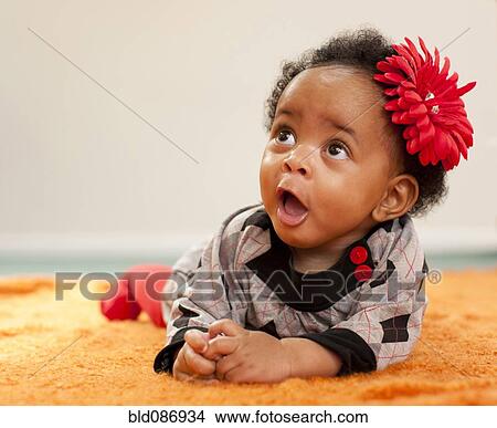Picture - African American baby girl with red flower in her hair. Fotosearch