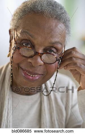 Stock Photography - Black woman adjusting eyeglasses. Fotosearch