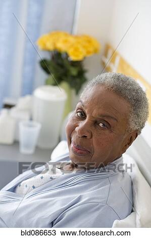 Stock Image - Black woman recovering in hospital bed. Fotosearch