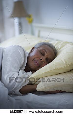 Stock Image - Black woman sleeping in bed. Fotosearch