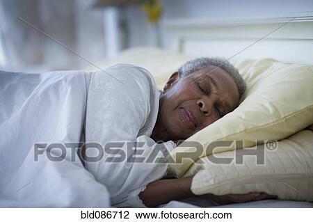 Stock Image - Black woman sleeping in bed. Fotosearch