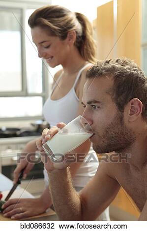 Stock Image - Caucasian man drinking milk in kitchen. Fotosearch