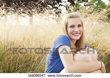 Stock Photo - Caucasian teenager sitting in grass. Fotosearch