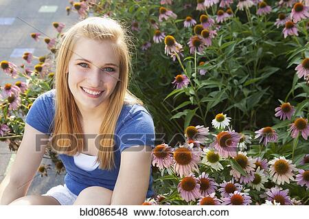Stock Photo - Caucasian teenager sitting near flowers. Fotosearch