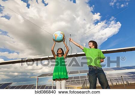 Stock Image - Children holding globe near solar panels. Fotosearch