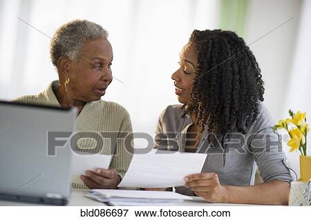 Stock Photo - Daughter helping mother pay bills online. Fotosearch