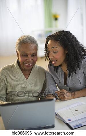 Stock Photograph - Daughter using laptop with mother. Fotosearch