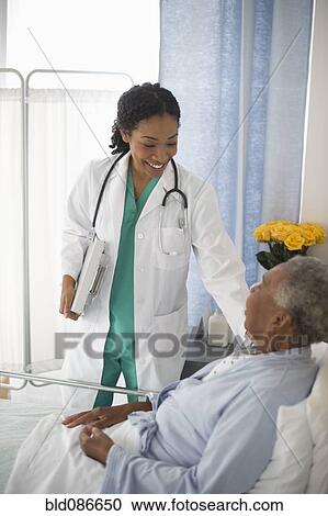 Stock Image - Doctor checking on patient in hospital. Fotosearch
