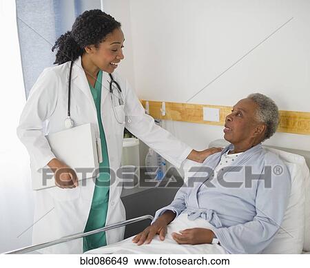 Doctor checking on patient in hospital View Large Photo Image Stock Photo - Doctor checking on patient in hospital. Fotosearch