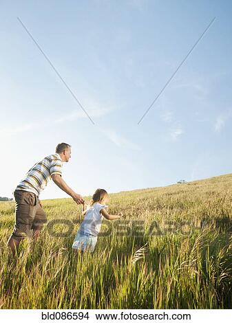 Picture - Father and daughter walking up hill together. Fotosearch