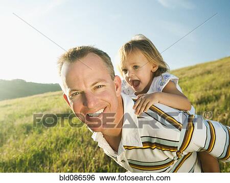 Father carrying daughter on his back in field View Large Photo Image Stock Photograph - Father carrying daughter on his back in field. Fotosearch