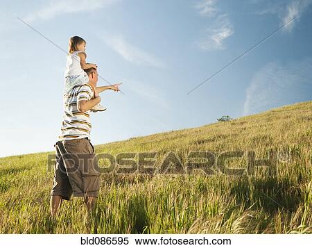 Stock Photography - Father carrying daughter on shoulders in field. Fotosearch