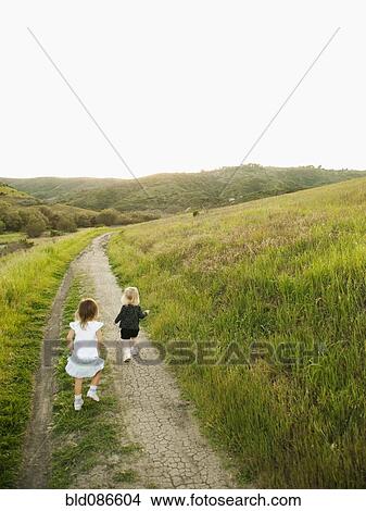 Picture - Girls walking on path in field. Fotosearch
