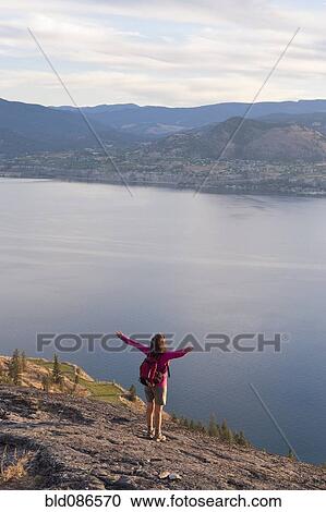 Hispanic hiker standing on cliff over lake View Large Photo Image Stock Image - Hispanic hiker standing on cliff over lake. Fotosearch