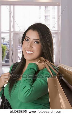 Stock Photography - Hispanic woman carrying shopping bags. Fotosearch