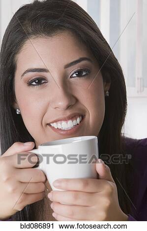 Stock Image - Hispanic woman drinking coffee. Fotosearch