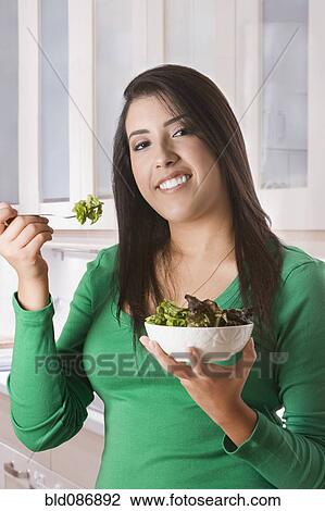 Stock Image - Hispanic woman eating salad. Fotosearch