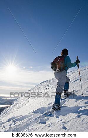 Stock Photograph - Hispanic woman snowshoeing up hill. Fotosearch