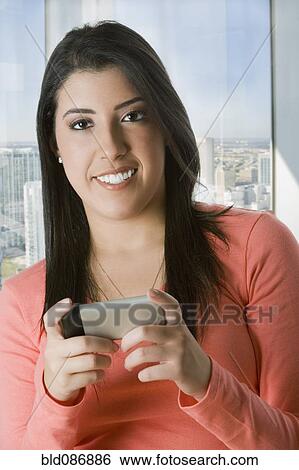 Stock Photograph - Hispanic woman text messaging on cell phone. Fotosearch