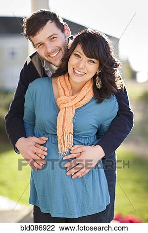 Stock Image - Husband hugging pregnant wife's stomach. Fotosearch