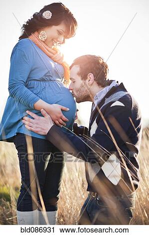 Stock Image - Husband kissing pregnant woman's stomach. Fotosearch