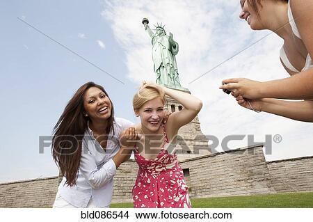 Picture - Laughing friends visiting the Statue of Liberty. Fotosearch