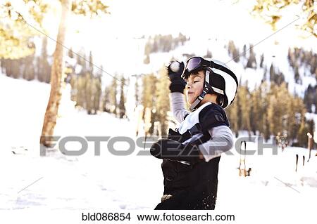 Picture - Mixed race boy in helmet having snowball fight. Fotosearch