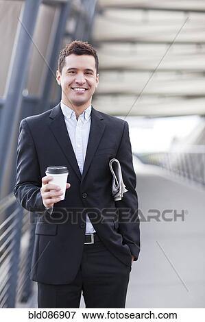 Mixed race businessman carrying coffee and newspaper View Large Photo Image Stock Photo - Mixed race businessman carrying coffee and newspaper. Fotosearch