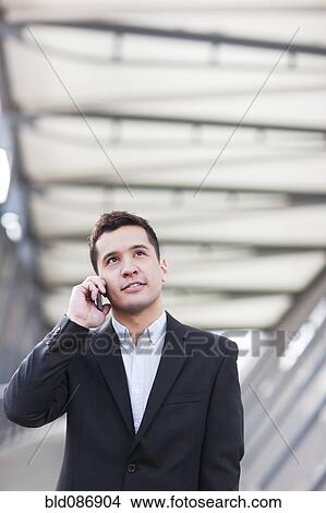 Picture - Mixed race businessman talking on cell phone. Fotosearch