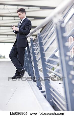 Stock Photography - Mixed race businessman text messaging on cell phone. Fotosearch