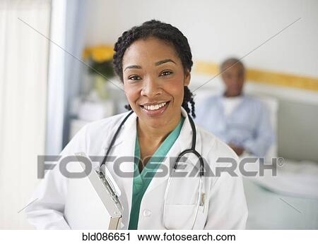 Stock Image - Mixed race doctor making rounds in hospital. Fotosearch