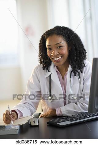 Stock Photography - Mixed race doctor working at desk. Fotosearch