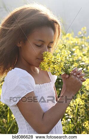 Stock Photo - Mixed race girl smelling flowers. Fotosearch