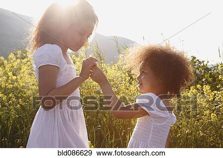 Mixed race girls smelling flowers View Large Photo Image Stock Photo - Mixed race girls smelling flowers. Fotosearch