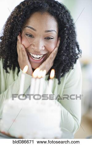 Stock Image - Mixed race woman looking at birthday cake. Fotosearch