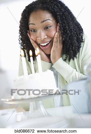 Stock Image - Mixed race woman looking at birthday cake. Fotosearch