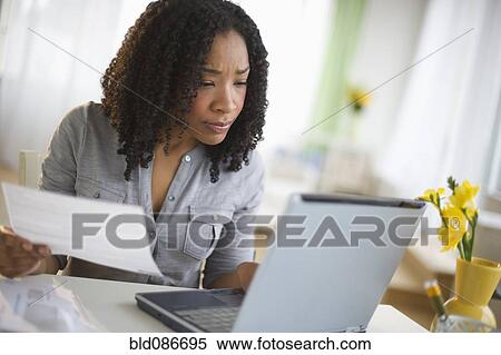 Stock Photography - Mixed race woman paying bills online. Fotosearch