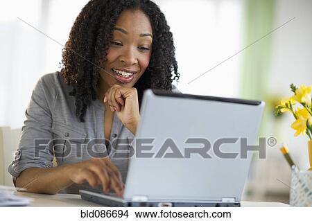 Picture - Mixed race woman using laptop. Fotosearch