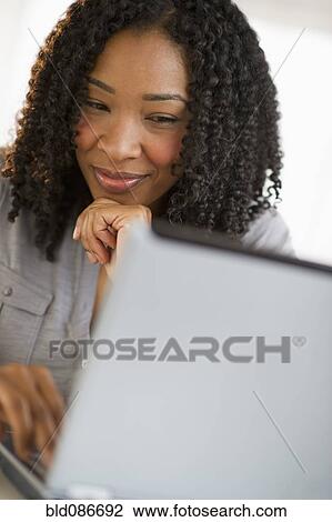 Stock Image - Mixed race woman using laptop. Fotosearch