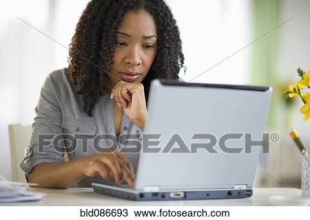 Stock Image - Mixed race woman using laptop. Fotosearch