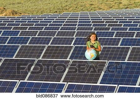 Stock Photo - Native American girl standing near solar panels holding globe. Fotosearch