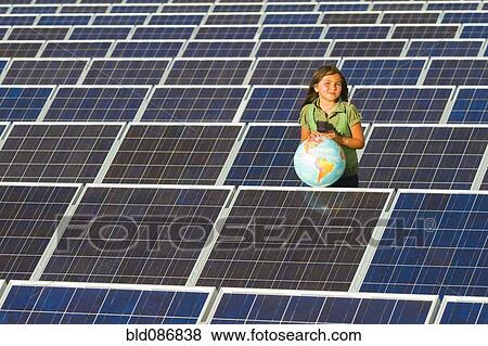 Stock Photo - Native American girl standing near solar panels holding globe. Fotosearch